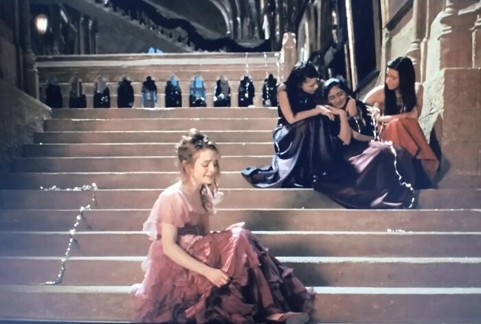 Four women in evening dresses sitting on stone steps, highlighting questionable movie details in a dramatic scene.
