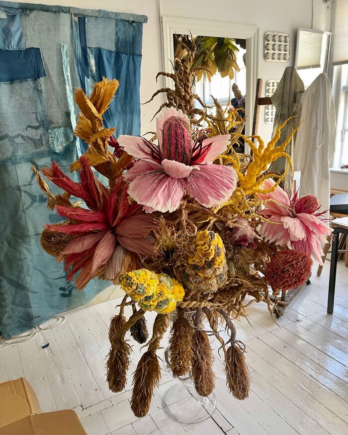 Giant tissue paper flowers in pink, yellow, and red displayed in a bright studio with natural light and decor.