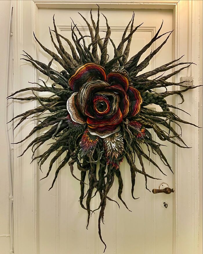Giant tissue paper flower with dark twisted petals and intricate details displayed on a white door.
