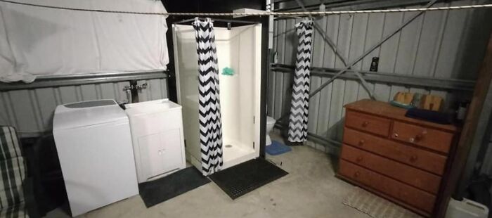 Run-down basement laundry area with shower, washing machine, and wooden dresser, illustrating bad landlords' poor rental conditions.