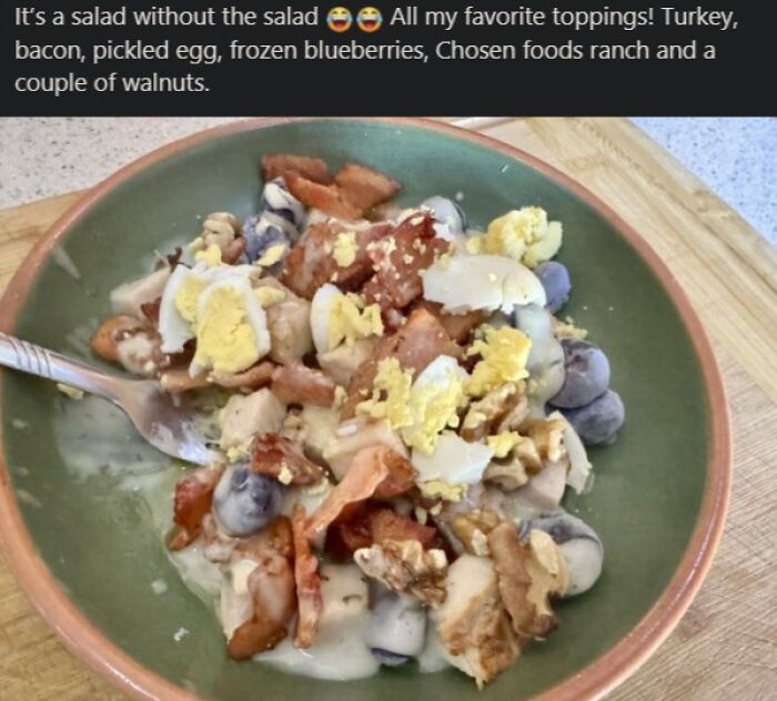 Salad without lettuce featuring turkey, bacon, pickled egg, frozen blueberries, ranch, and walnuts in a bowl.