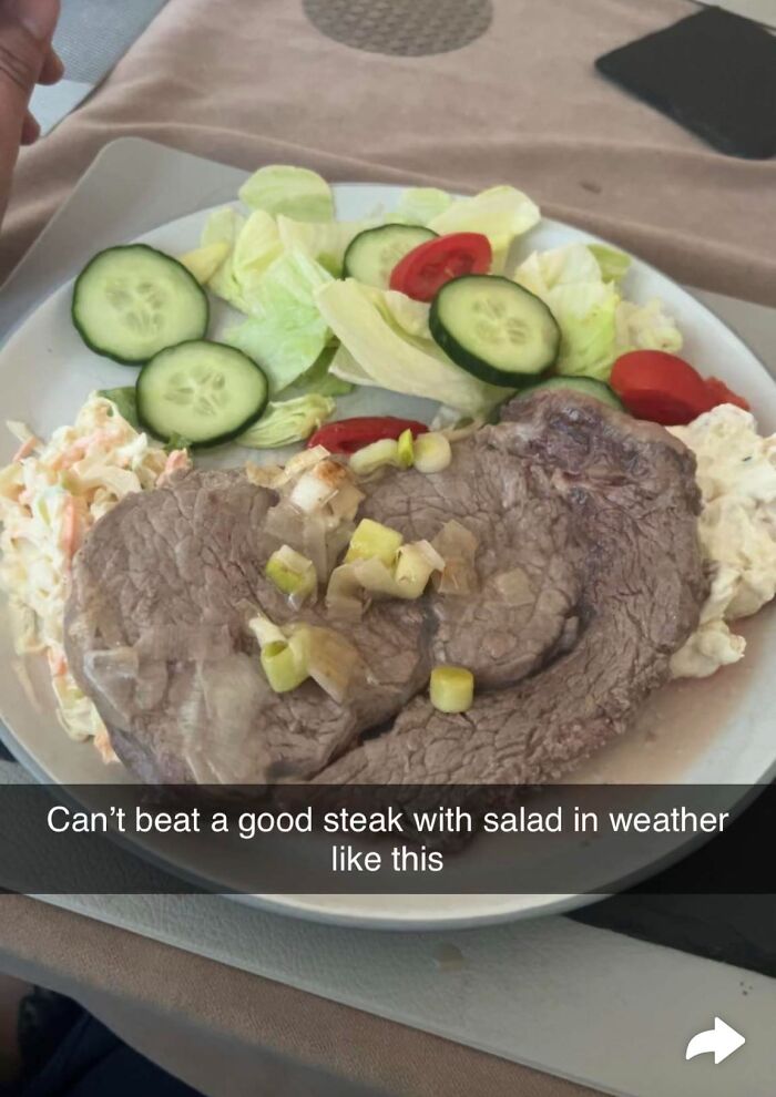 Plate with a grayish steak topped with onions, side salad of cucumber and tomatoes, showcasing cursed food pics.