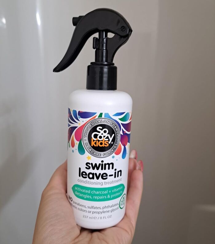 Bottle of So Cozy Kids swim leave-in conditioning treatment held by hand, a viral summer essential for hair care.