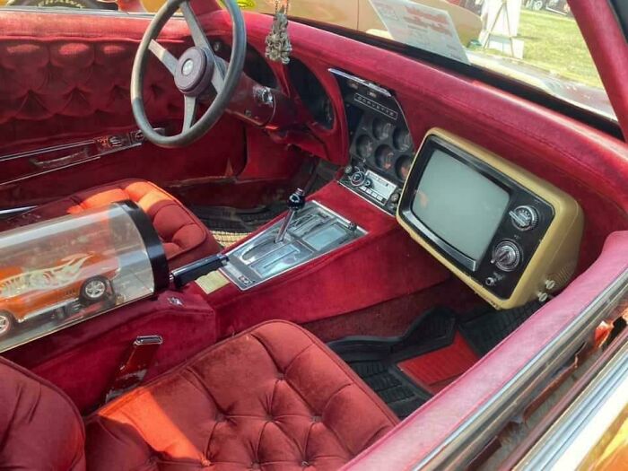 Vintage car interior with built-in CRT television and tufted red upholstery showcasing vintage devices technology.