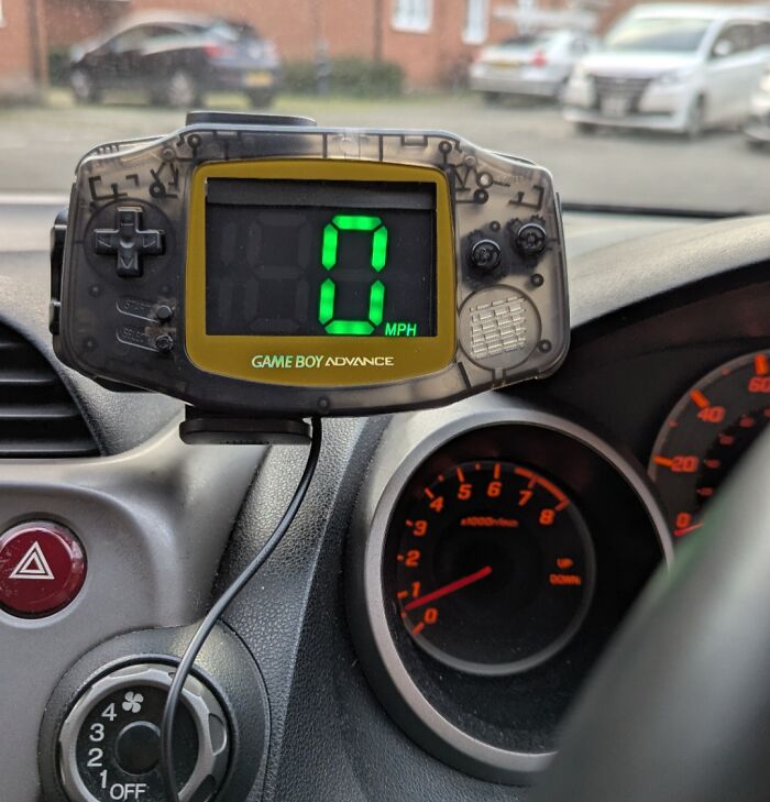 Vintage Game Boy Advance repurposed as a digital speedometer inside a car, showcasing vintage devices technology.