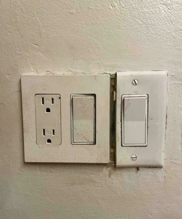Old dirty light switches and electrical outlet poorly installed with visible gap on wall, showing landlord specials flaws.