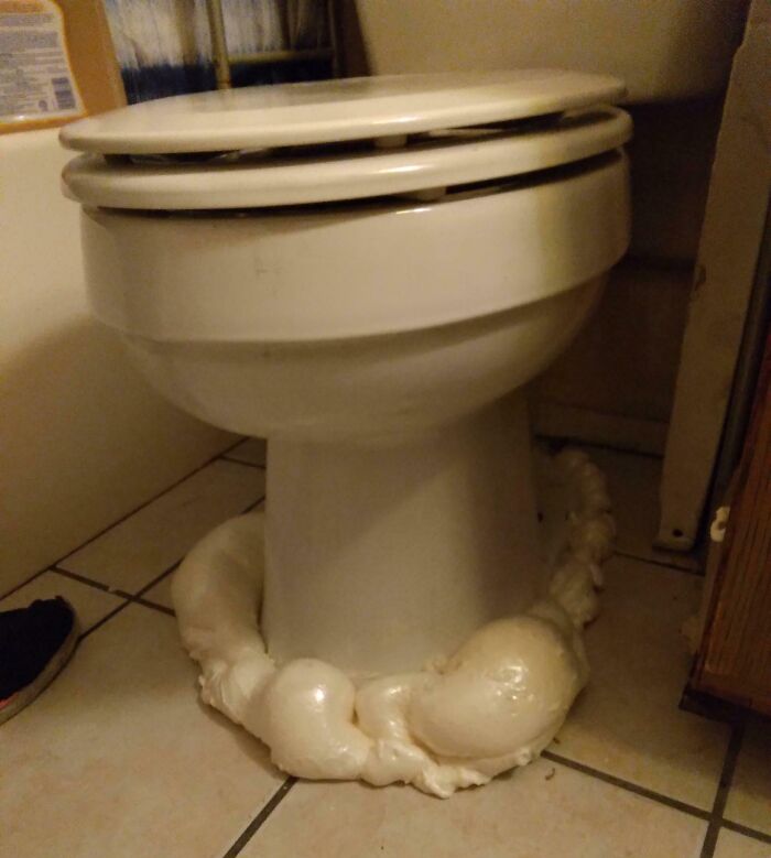Toilet base surrounded by overflowing foam sealant in a rental bathroom, an example of infuriating landlord neglect.