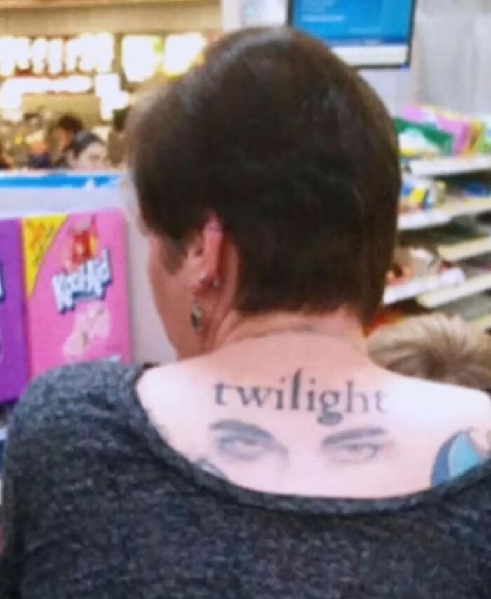 Woman with a funny and interesting tattoo of the word twilight and eyes on her upper back in a store setting.