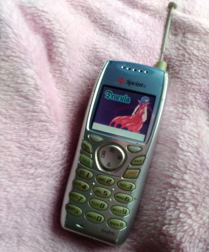 Vintage mobile phone with antenna displaying a colorful game, showcasing vintage devices in technology history.