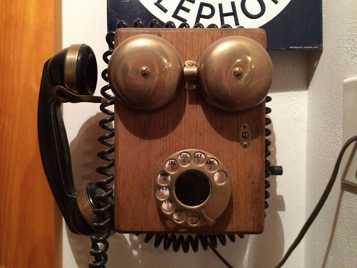 Vintage wooden rotary telephone with brass bells and coiled cord, showcasing classic vintage devices in technology history.