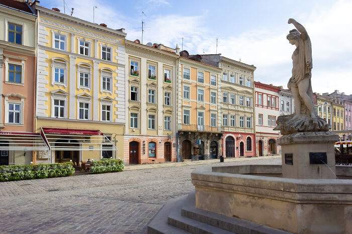 Historic square with colorful buildings and a statue fountain, showcasing stunning UNESCO treasures in a picturesque European town.