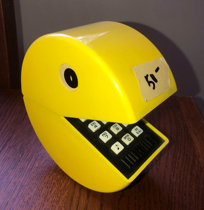 Yellow vintage device shaped like a smiling character with buttons, showcasing unique technology from past decades.