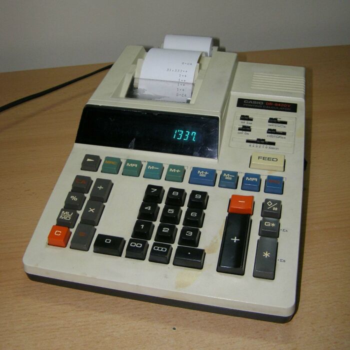 Vintage printing calculator on wooden desk, showcasing classic buttons and display as a vintage device in technology history.