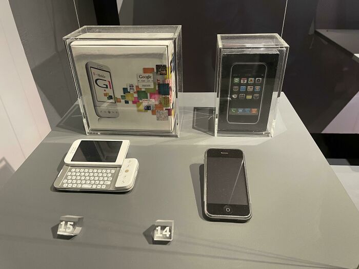 Vintage devices including early smartphones and a slide-out keyboard phone displayed in a technology exhibit showcasing vintage devices.