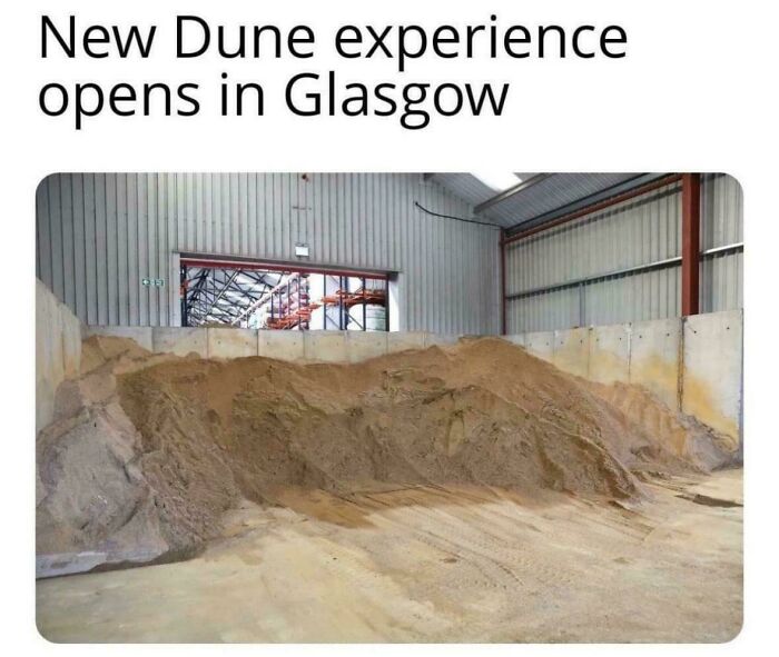 Indoor sandpile in a warehouse humorously labeled as a new Dune experience in Glasgow for British memes fans.