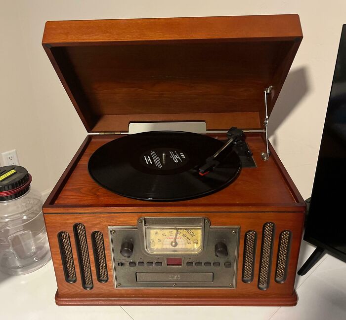 Vintage record player with wooden casing and analog controls, showcasing vintage devices and technology evolution.