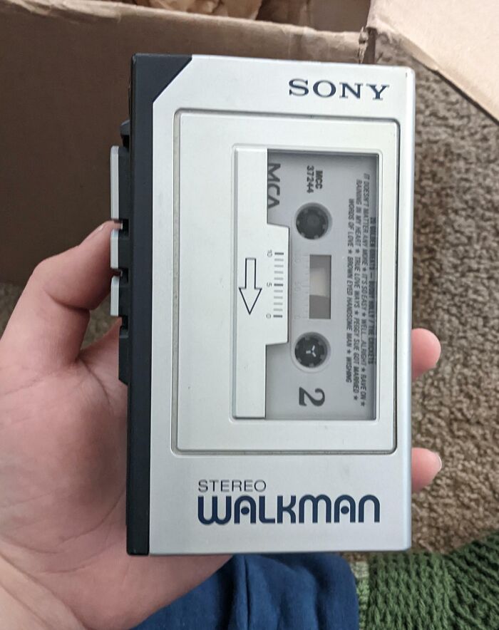 Hand holding a vintage Sony Walkman with cassette tape, showcasing classic technology and vintage devices.
