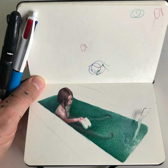 Hand holding a tiny sketchbook with a colored drawing of a person in a green pool, showcasing big emotions in small art.
