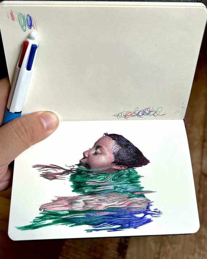 Hand holding tiny sketchbook with colorful ballpoint pen drawing of a person, showing everyday moments in art.
