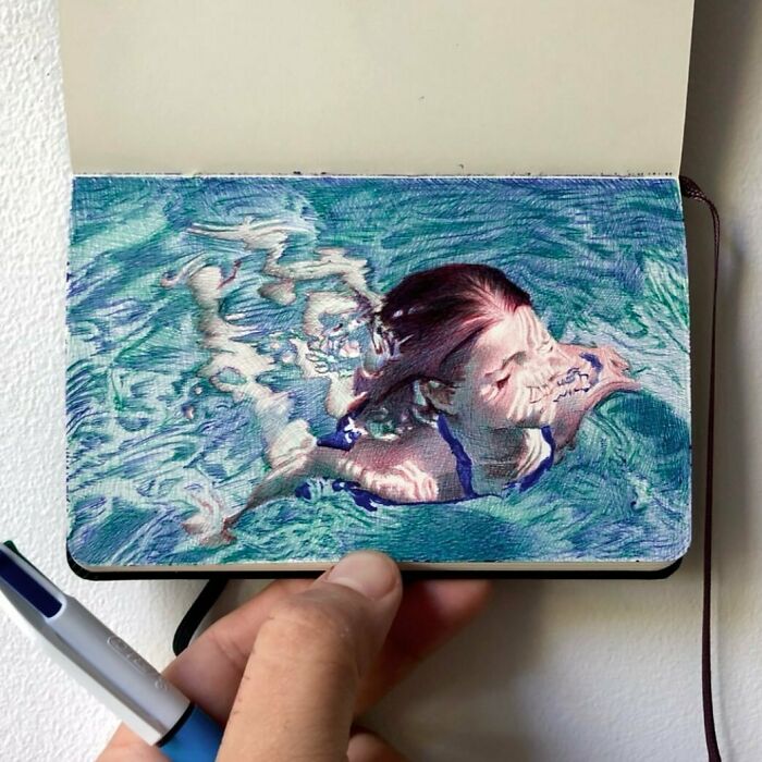 Hand holding tiny sketchbook with detailed colored pencil drawing of a swimmer reflecting big emotions in everyday moments.