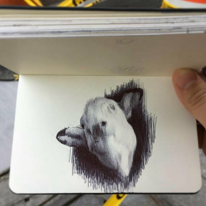 Hand holding a tiny sketchbook featuring a detailed pen drawing of a rabbit, showcasing big emotions in small art.