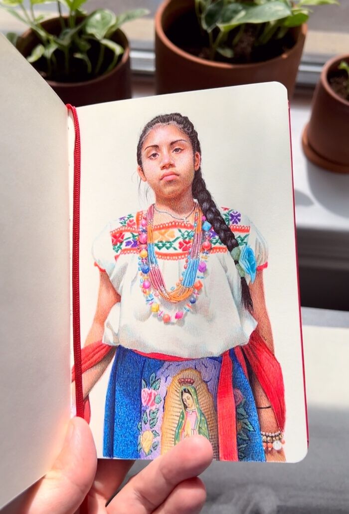 Hand holding tiny sketchbook with detailed colored portrait, showcasing big emotions in everyday moments artwork.