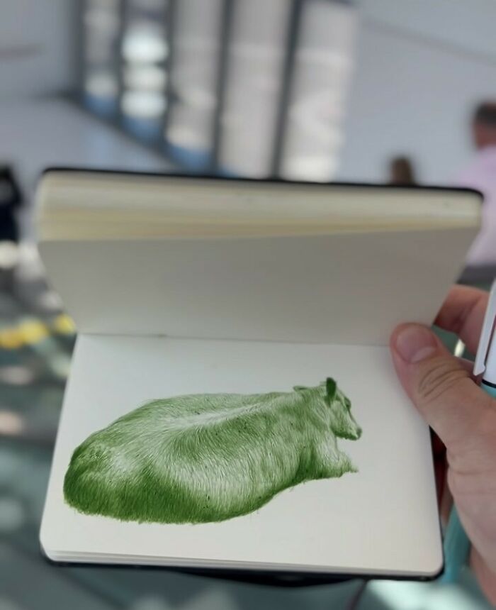 Hand holding a tiny sketchbook showing a detailed green drawing of a resting animal, highlighting big emotions in art.