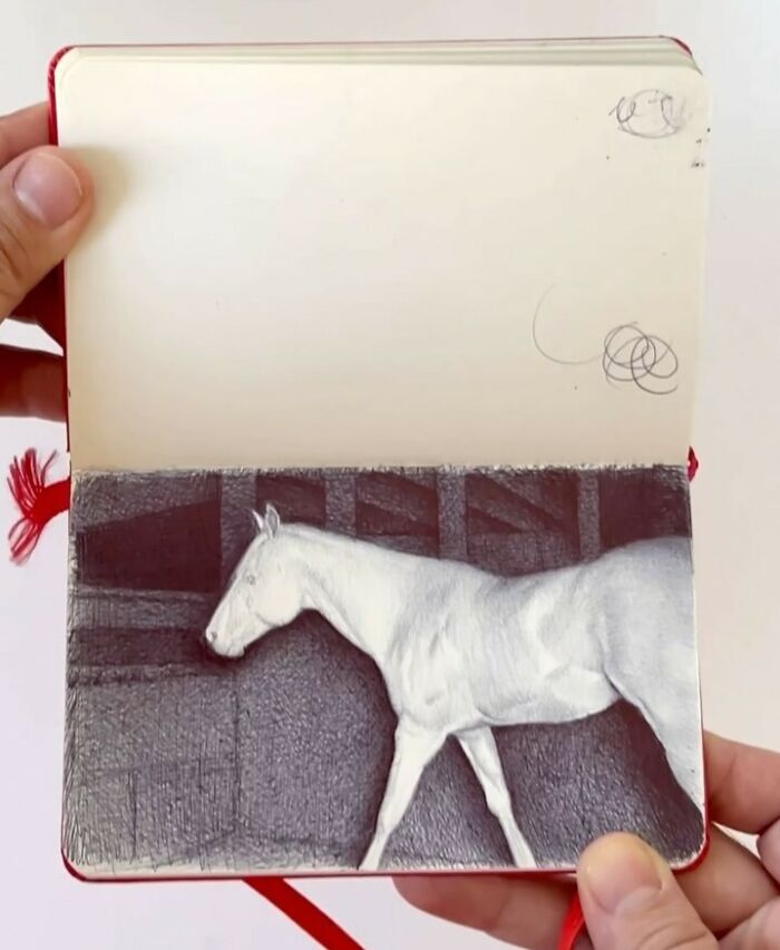 Hand holding tiny sketchbook with detailed pencil drawing of a white horse, showcasing big emotions in everyday moments.