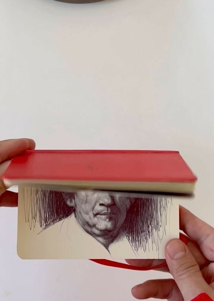 Hand flipping through tiny sketchbook showing detailed portrait drawing, highlighting big emotions in everyday moments artwork.