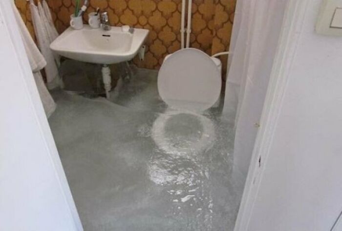 Bathroom renovation fail with flooded floor after attempted cheap plumbing fix causing water overflow and damage.