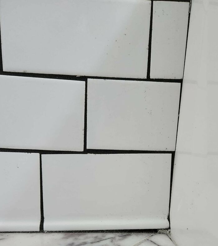 Unevenly installed white tiles with visible grout mistakes, showcasing a renovation fail and saving gone wrong.