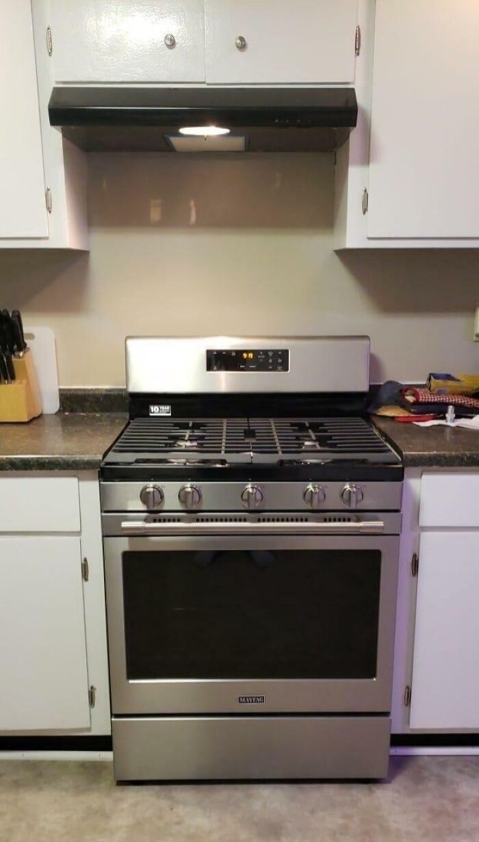Modern gas stove installed under a range hood, surrounded by white cabinetry in a home renovation fail.