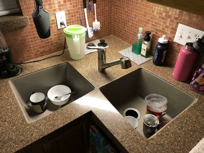 Double kitchen sink with mismatched depths showing renovation fail in a small space with various items around the countertop.