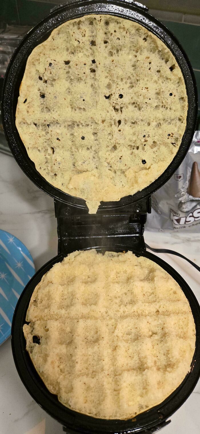Waffle maker with an incomplete, unevenly cooked waffle showing a classic cooking fail in the kitchen.