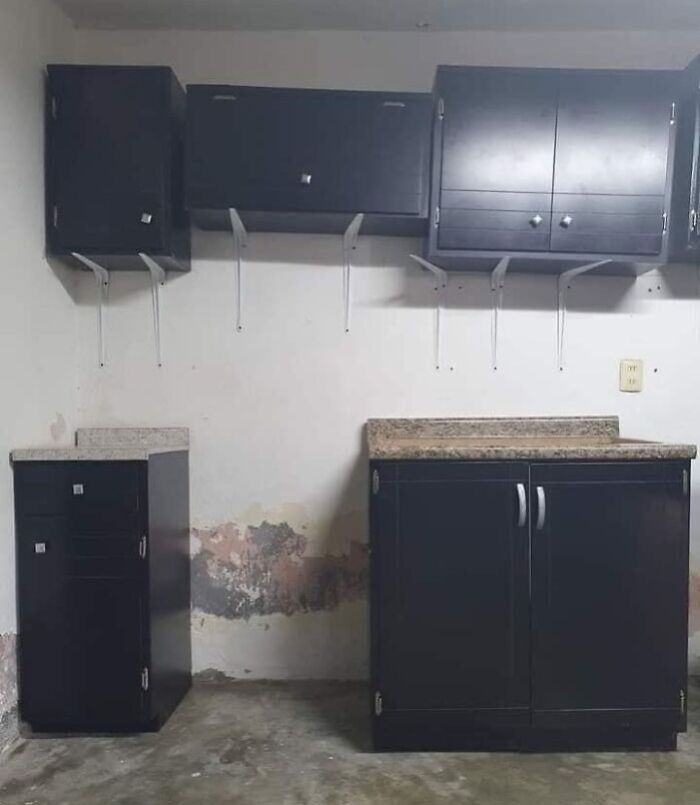 Kitchen renovation fail with poorly installed cabinets and damaged wall showing saving on renovations regret humor.