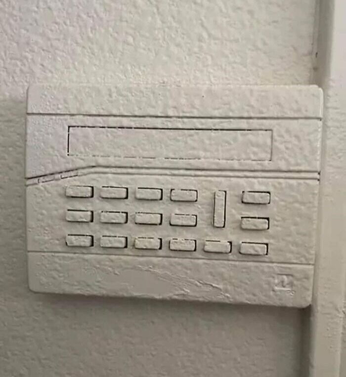 Security keypad covered in thick paint, showing a renovation fail where saving money led to instant regret.