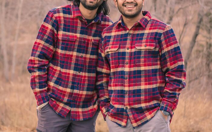 Two men wearing matching plaid flannel shirts, showcasing cringey nineties fashions we left behind outdoors.