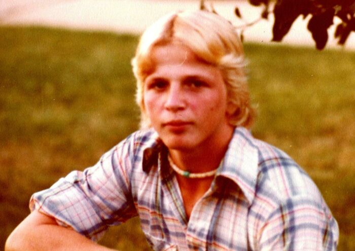 Teen boy outdoors wearing a plaid shirt and shell necklace, showcasing cringey nineties fashions left behind.