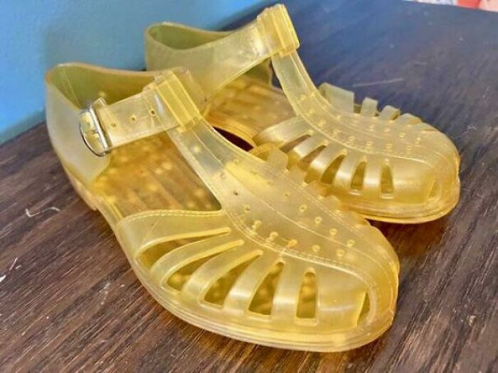 Yellow translucent jelly shoes from the nineties displayed on a wooden surface, representing cringey nineties fashion trends.