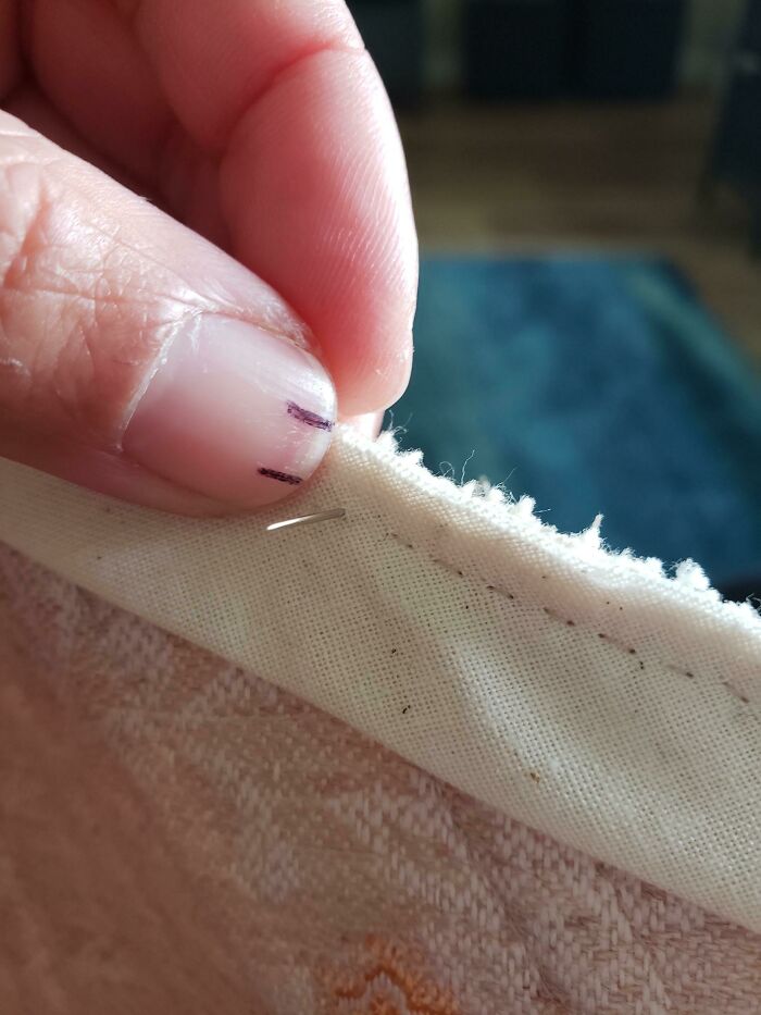 Close-up of a hand fixing fabric with a needle, showcasing a clever way people solved overlooked issues.