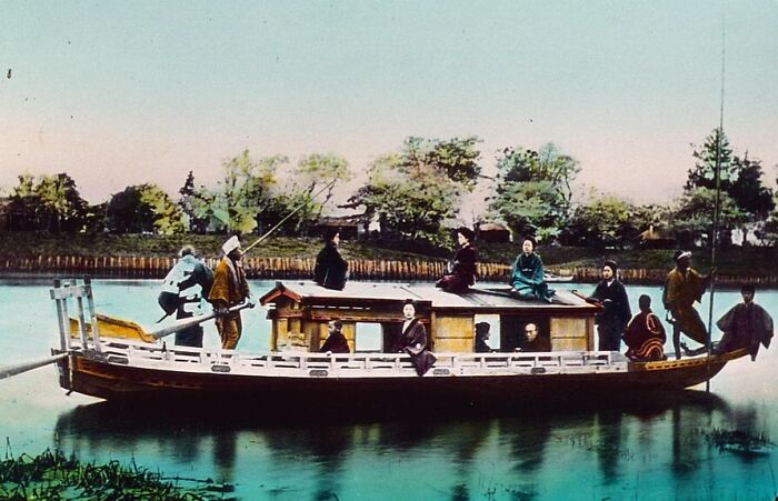 Historic commutes on a traditional wooden boat with passengers crossing a calm river in a bygone working world.