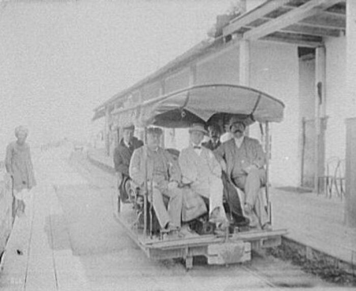 Historic commutes showing men in early 20th-century rail vehicle, capturing a bygone working world scene at a train platform.
