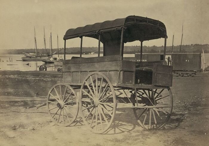 Vintage horse-drawn carriage parked near a waterfront, depicting historic commutes in a bygone working world.