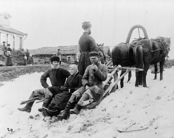 Historic commutes showing workers in traditional clothing riding a horse-drawn sled through a snowy rural area.