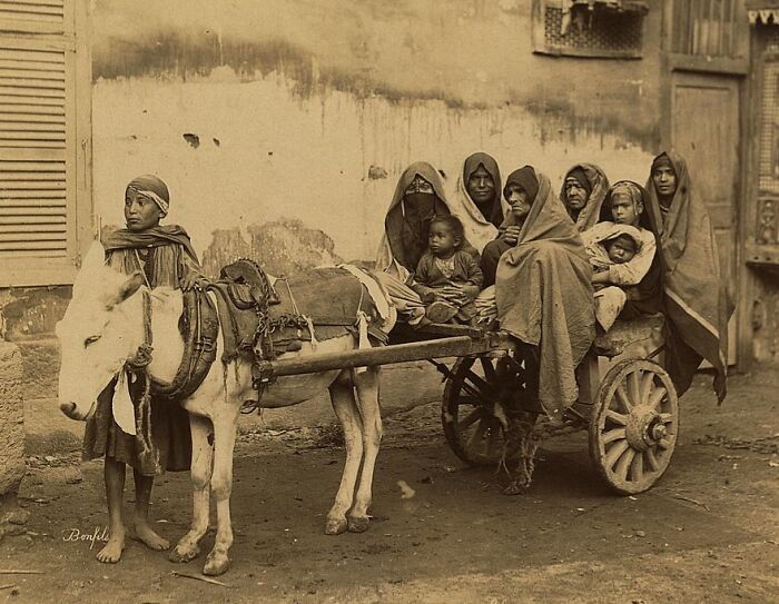 Historic commute scene with a group of people riding a donkey cart in a bygone working world setting.