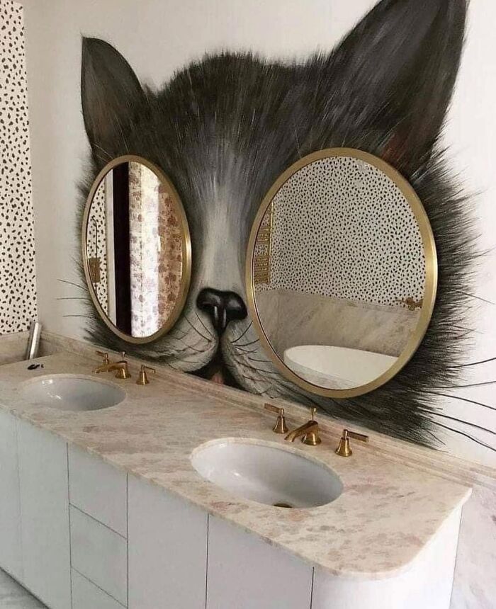 Bathroom double sink with round mirrors set in a cat face mural, an example of worst real estate photos ever in quirky homes.