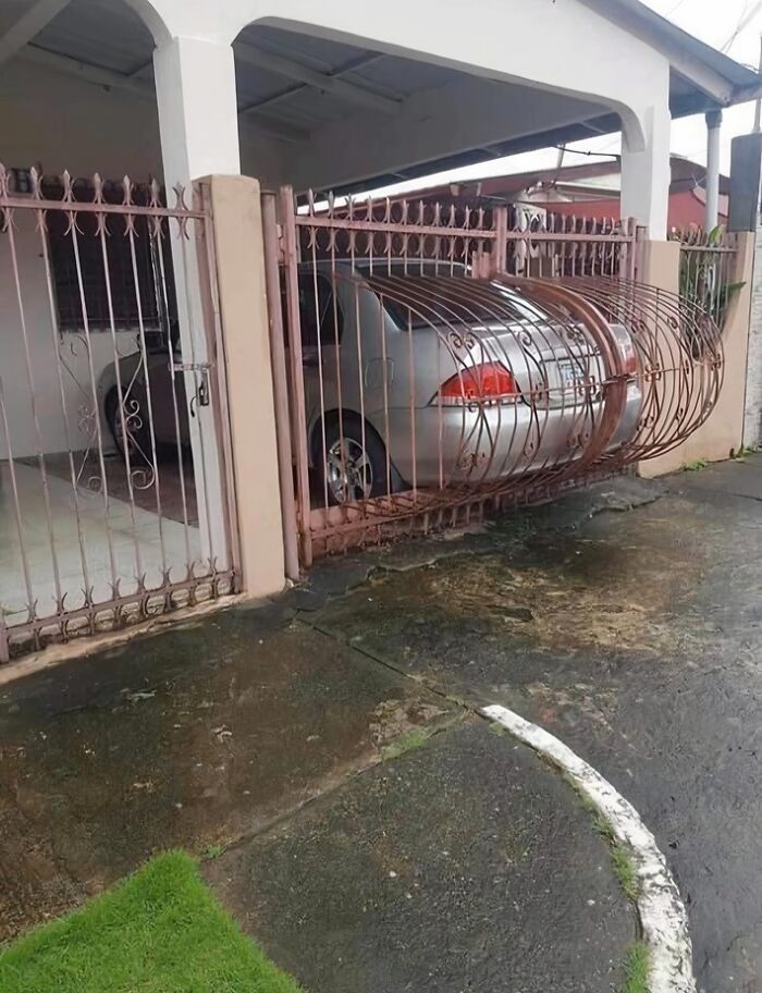 Car trapped behind a bent metal gate at a residential property showing worst real estate photos ever.