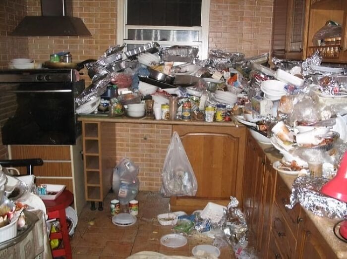 Cluttered kitchen with piles of dirty dishes, trash, and food containers, depicting worst real estate photos ever.