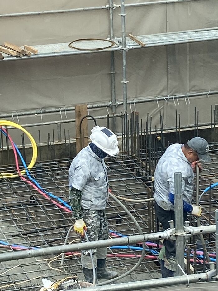 Two construction workers using clever solutions while working with pipes and rebar on a building site.