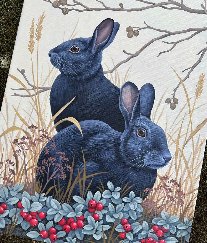 Two detailed nature-inspired paintings of dark blue rabbits in grass with red berries and dry branches.